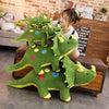 A green dinosaur plush toy with three smaller dinosaurs is displayed on a wooden shelf in a home setting.