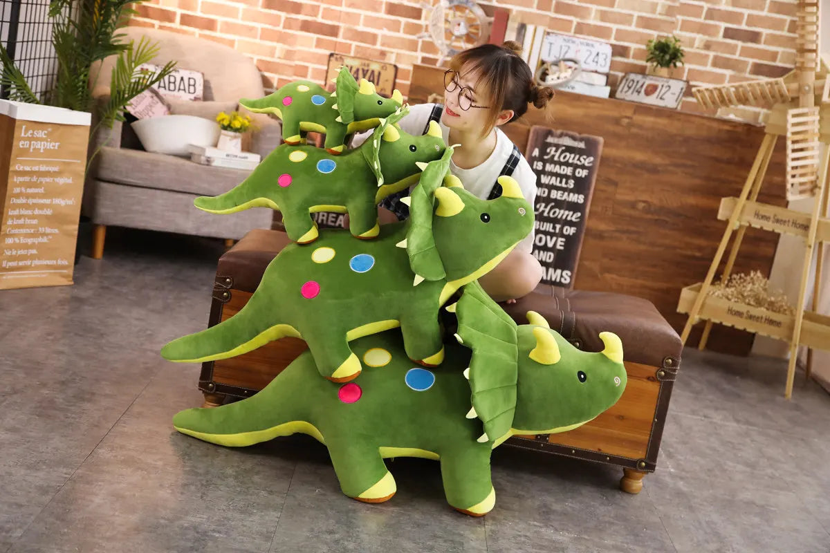A green dinosaur plush toy with three smaller dinosaurs is displayed on a wooden shelf in a home setting.
