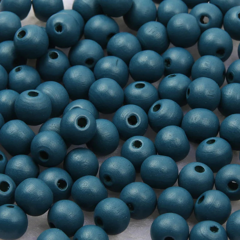 A pile of small, dark teal wooden beads for jewelry making and DIY crafts.