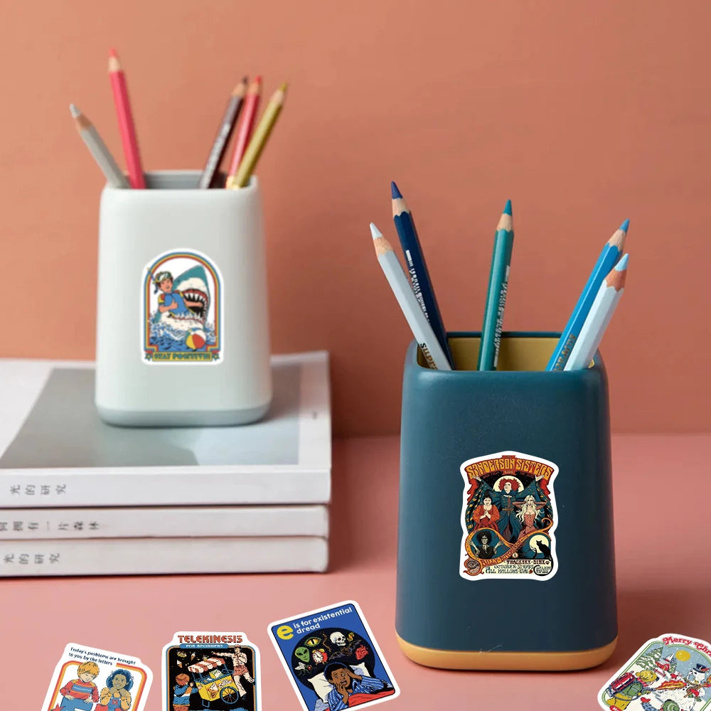 A teal ceramic mug filled with colored pencils sits next to a stack of books and a sticker pack.