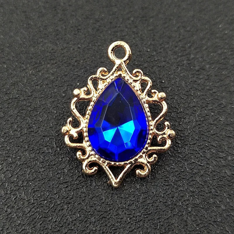 Gold plated water droplet charm featuring a deep blue crystal rhinestone set in an ornate flower design.