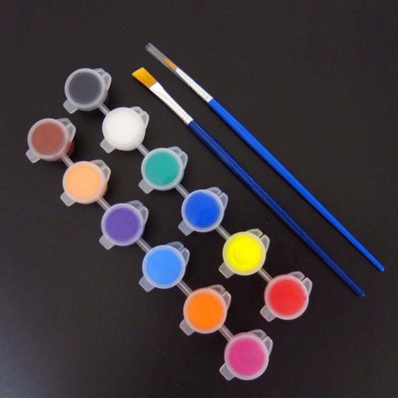 A set of twelve acrylic paint colors in small pots with brushes laid out on a dark surface.