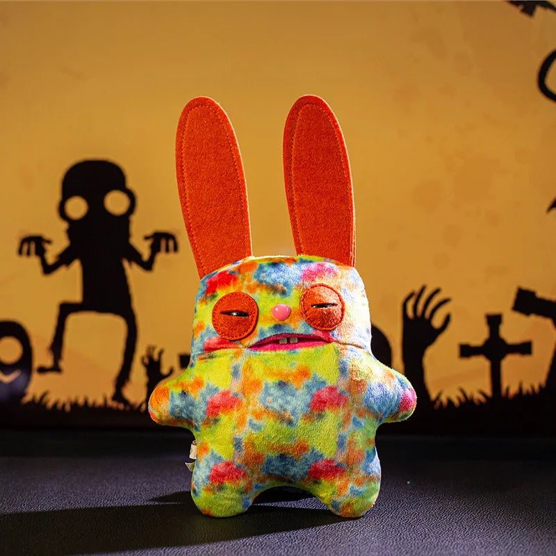 A colorful, fuzzy monster plush doll with large orange ears sits against a dark background.