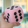 A hand holds a pink jumbo soft foam die with black dots, showing its texture and size.