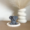 A gray elephant silicone mold sits on a white dish next to a large feathery plume.