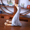 A gray long neck goose plush toy with orange feet sitting on a wooden surface.
