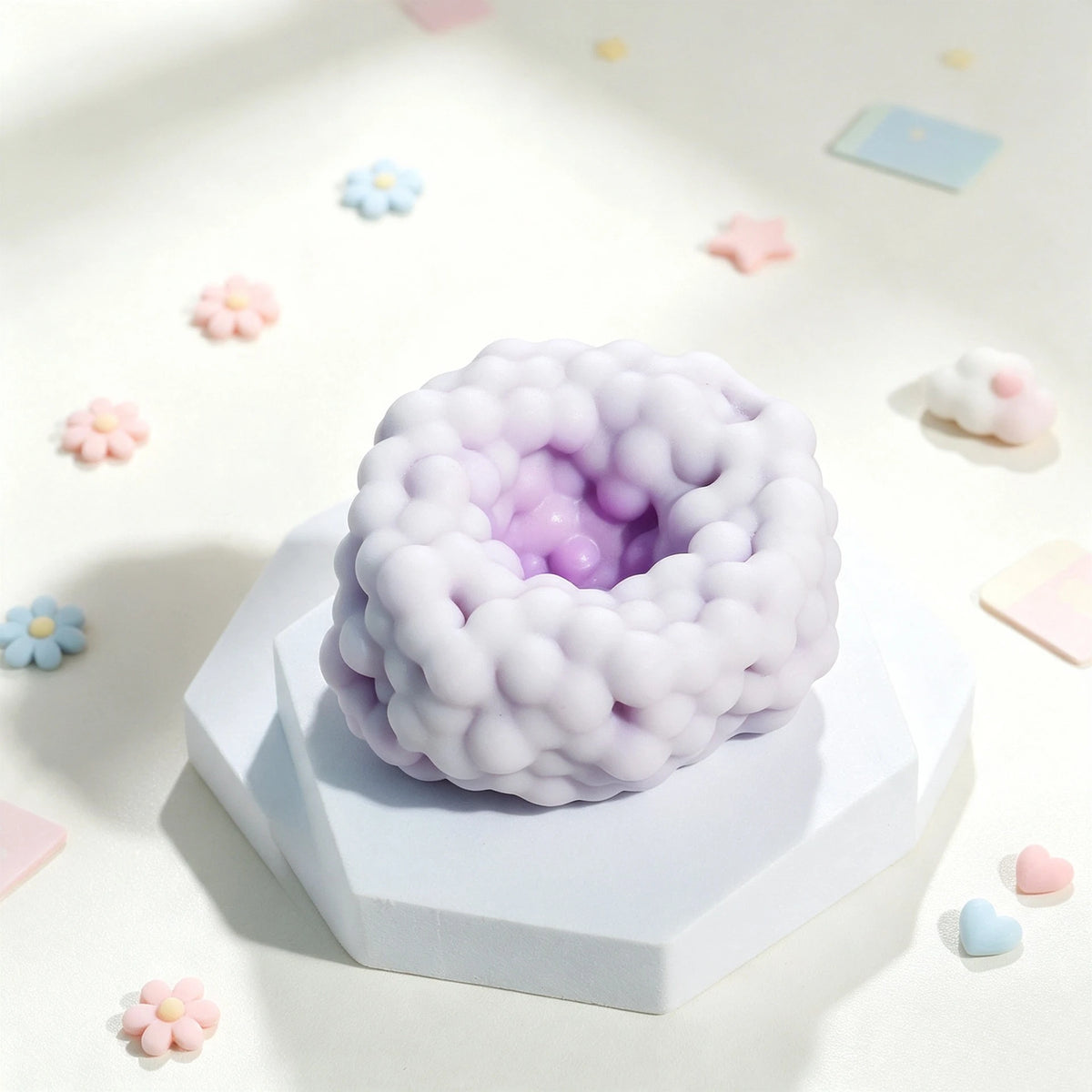 A light purple squishy sensory stress ball with a bubbly texture resting on a white block, surrounded by small pastel confett
