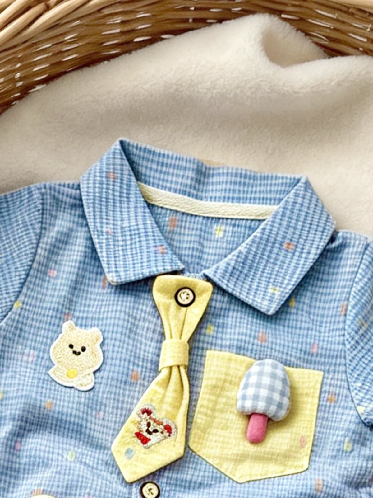 A light blue baby boy short-sleeve romper featuring yellow and white appliqués of a bear and a mushroom.