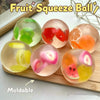 A collection of translucent fruit-shaped squishy balls in various colors like green, pink, orange, and yellow resting on a wo