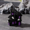 A black figurine of a house with purple windows and white pumpkin bear figures on the roof.