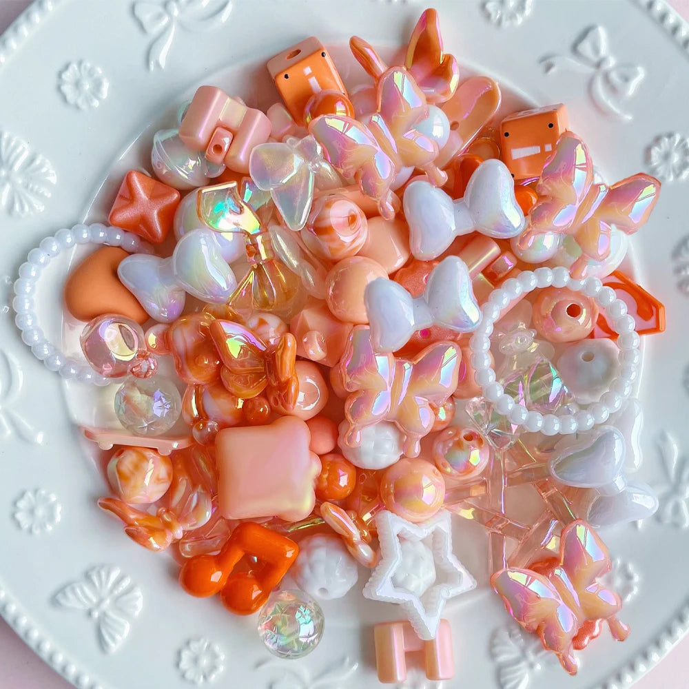 A collection of colorful acrylic bow and flower beads in pink, orange, and white are displayed on a white plate.