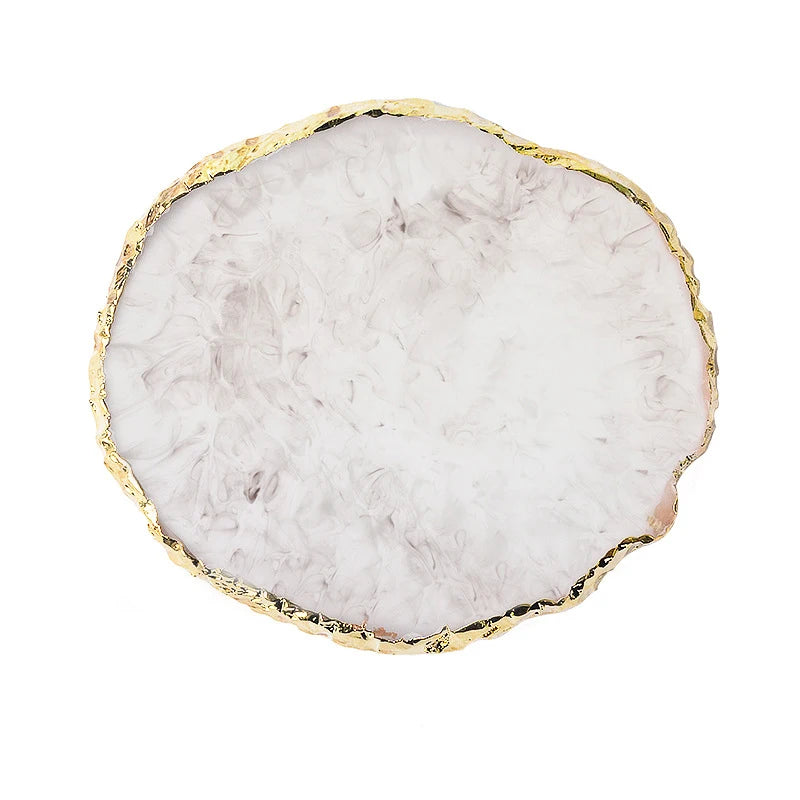 A round slab of white and gray resin with gold trim, used for nail art.