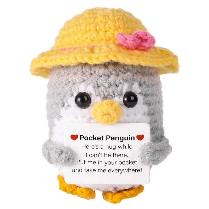Handmade crochet penguin doll with a yellow hat and a message card that reads Here's a hug while I can't be there.