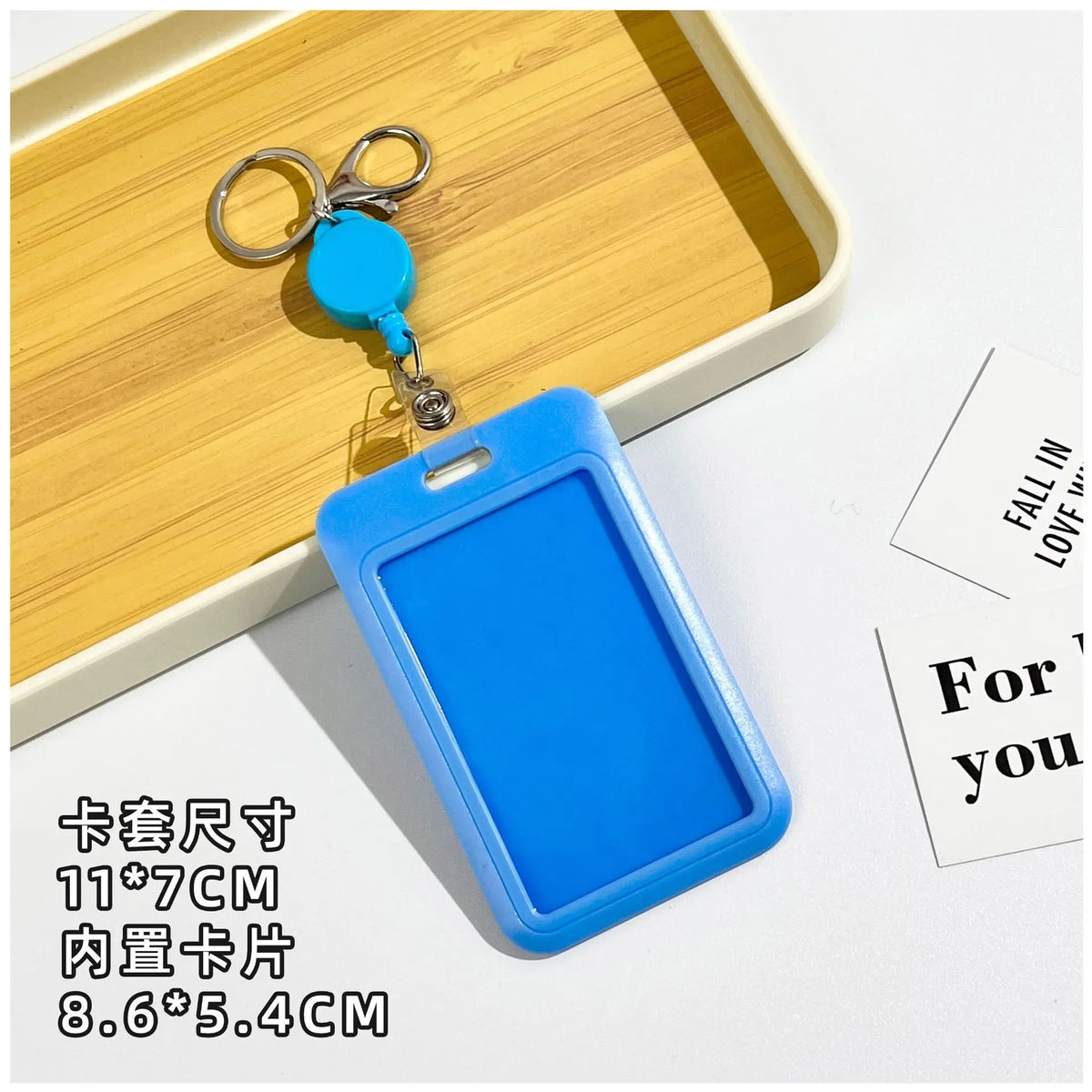 A bright blue plastic ID badge holder with a clip and keychain is displayed on a wooden tray.