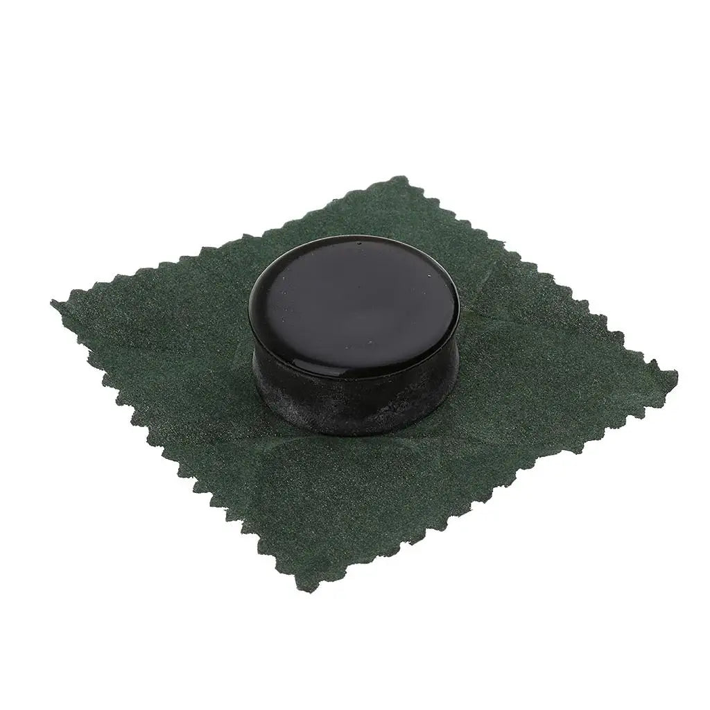 A small black tin of premium natural rosin for string instruments resting on a dark green cloth.