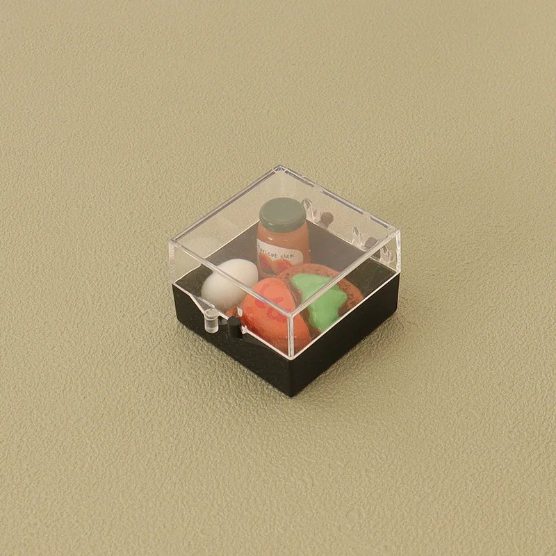 A clear plastic box contains miniature Japanese sushi items including a jar and various colored food pieces for a dollhouse k