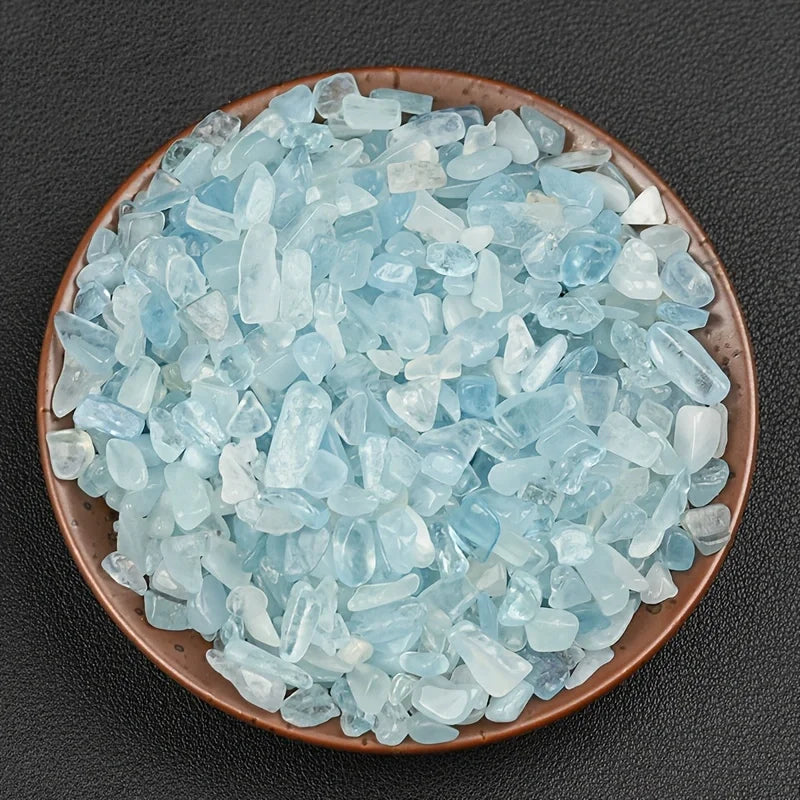A pile of light blue to translucent aquamarine chips in a shallow brown dish.
