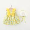 A yellow floral print baby girl summer dress with a bow and a white sunhat with a yellow ribbon