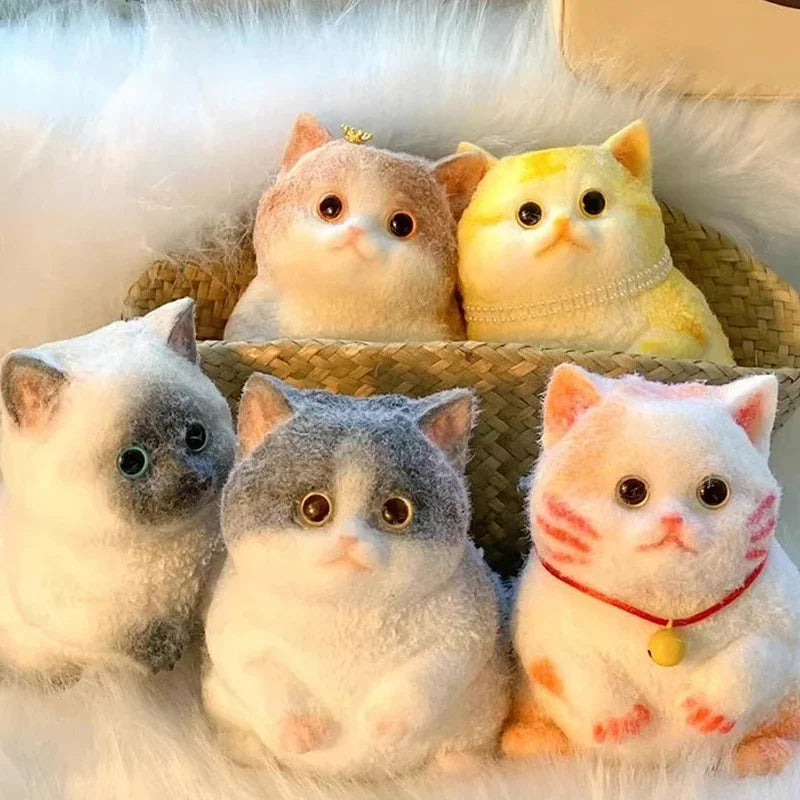 Collection de jouets en peluche à chats floccés de différentes couleurs et motifs posés sur un plateau tissé.