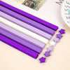 A collection of purple and white origami star strips laid out diagonally on a light background.