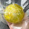 A yellow stress ball with gold glitter is wrapped in clear plastic film.