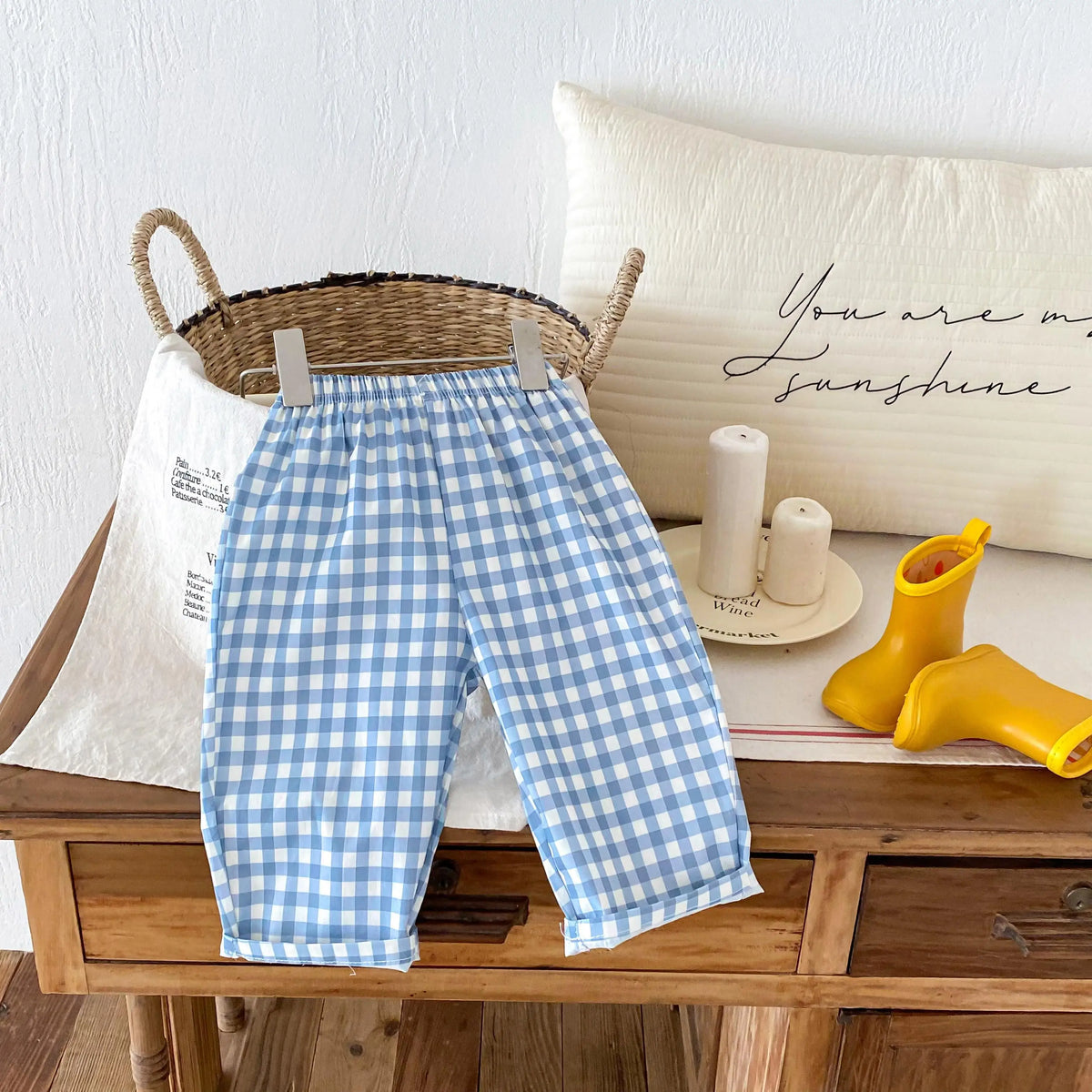 Light blue and white plaid casual pants with an elastic waist displayed on a wooden table.