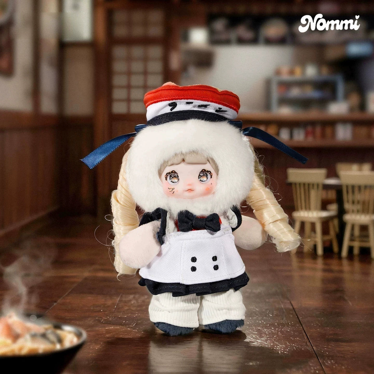 A fluffy white plush keychain of a character wearing a chef's hat and apron in an izakaya setting.