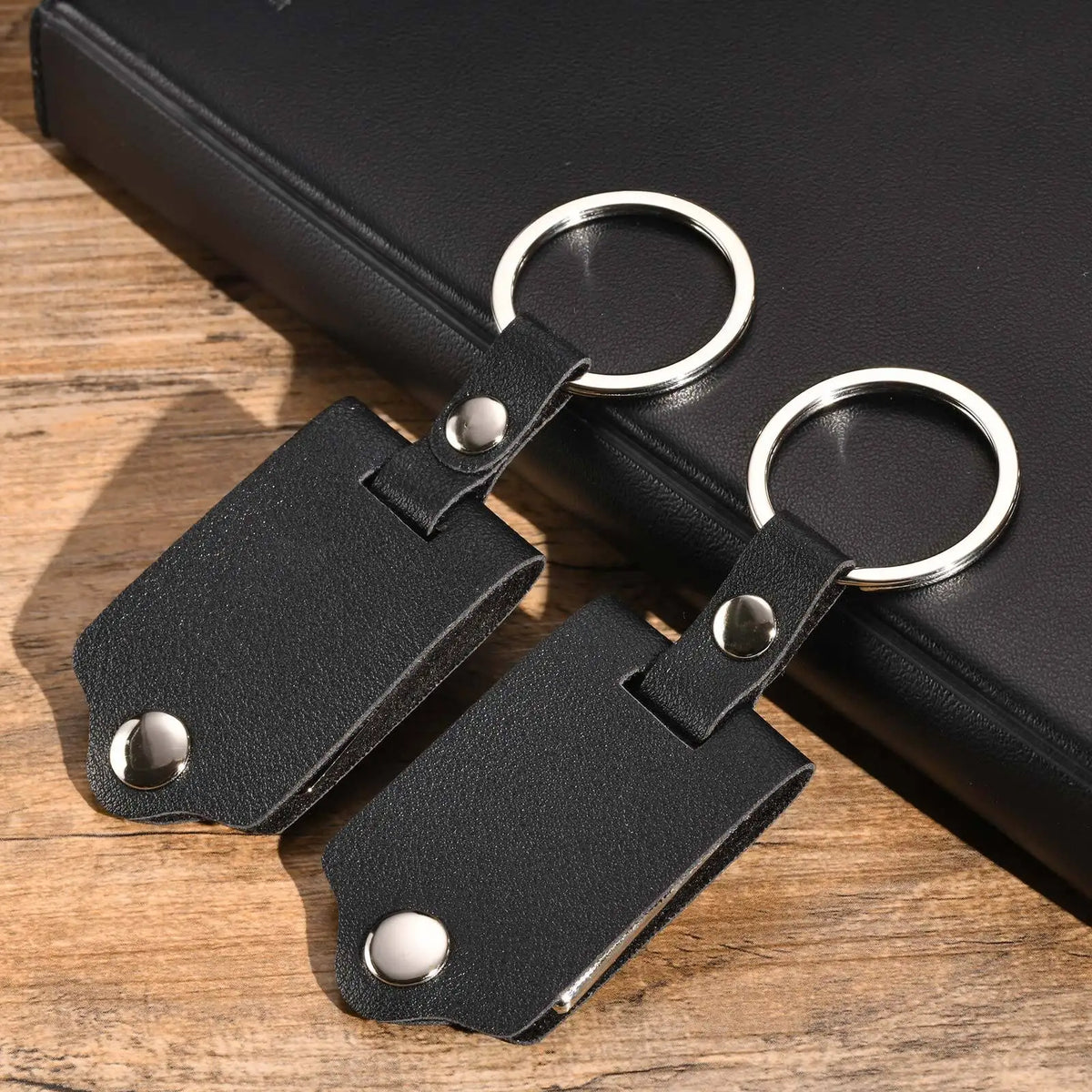 A black leather keychain with a custom photo attached, resting on a wooden surface.
