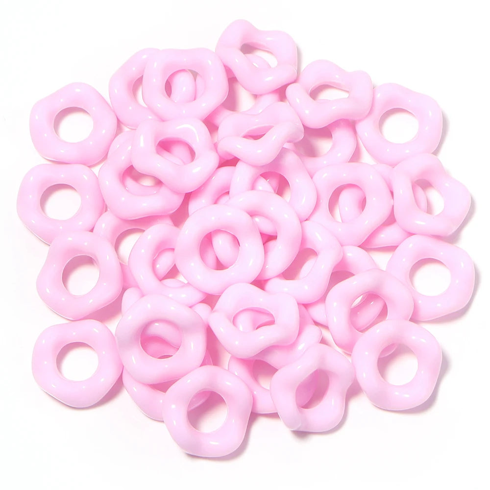 A pile of pink acrylic doughnut spacer beads for jewelry making