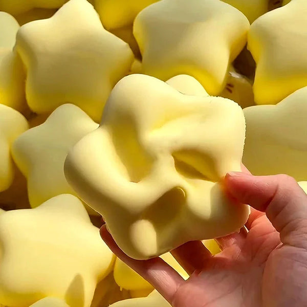 A hand is squeezing a yellow, star-shaped stress relief toy made of soft, squeezable material.