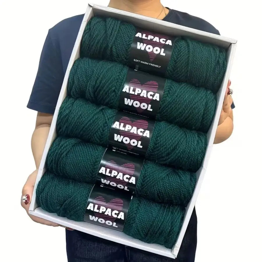 A pack of five skeins of dark green alpaca wool yarn for knitting and crochet projects.