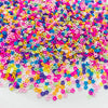 A pile of colorful polymer clay star and heart sprinkles in various shades of pink, purple, yellow, and blue.