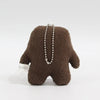 A brown, fuzzy plush toy with a necklace charm is displayed against a white background.