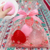 A clear bag filled with pink and red strawberry squishy toys, including a large pink strawberry and a smaller red strawberry.