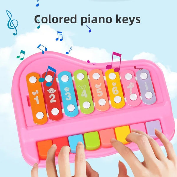A hand is pressing colored piano keys on a pink plastic instrument set for toddlers.