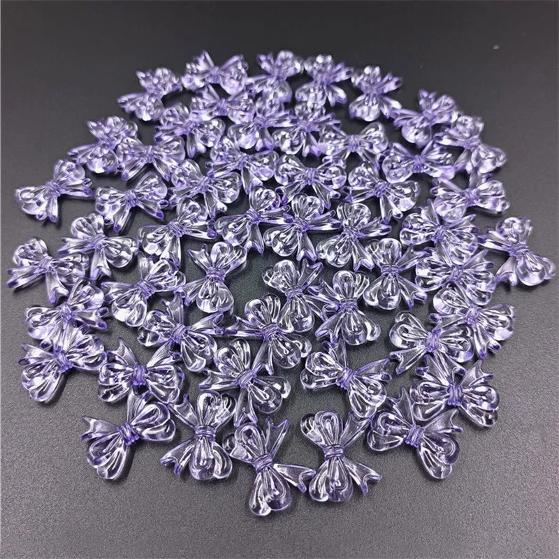A pile of 20 clear purple acrylic bow beads for jewelry making