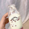 A hand holds a glass bottle filled with white liquid labeled Chiboki drink cup toy