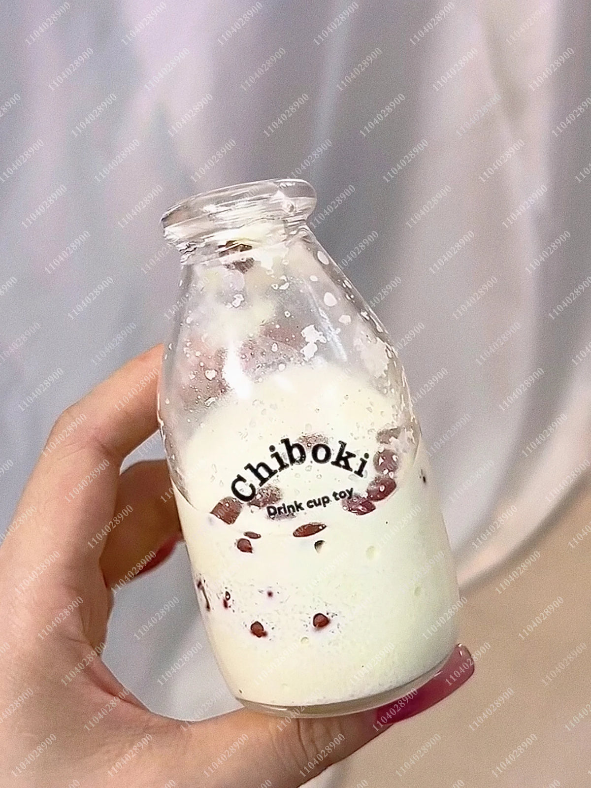 A hand holds a glass bottle filled with white liquid labeled Chiboki drink cup toy