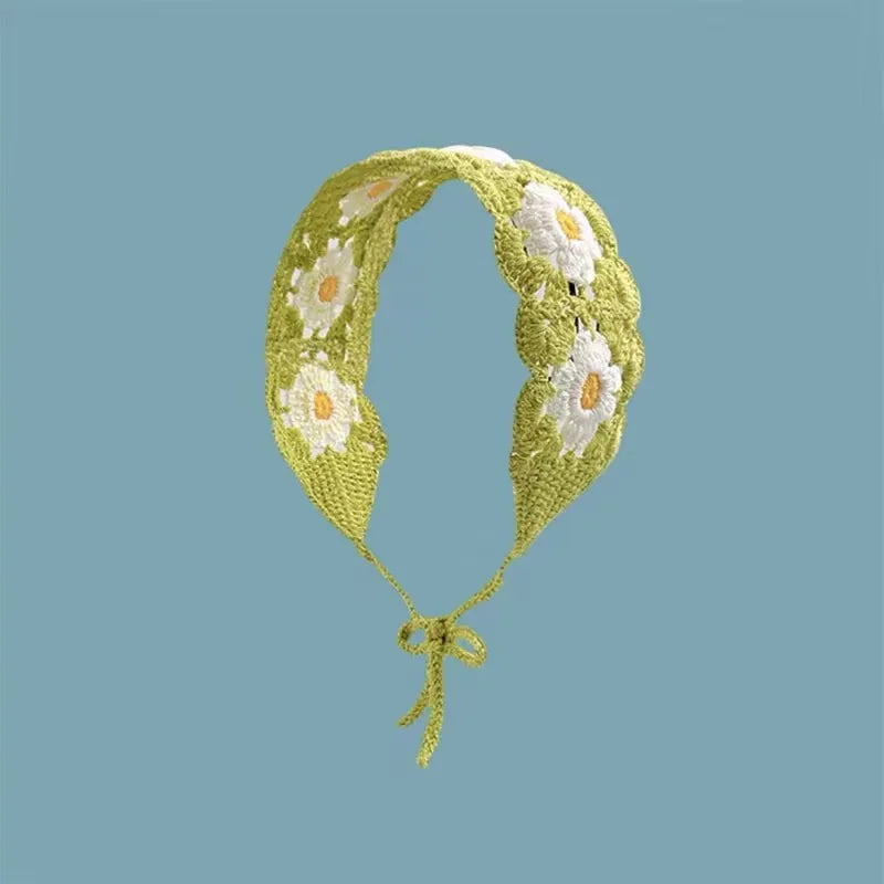 A light green crochet headband decorated with white and yellow floral patterns.