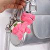 A pink and white turtle plush keyring charm attached to a silver backpack strap.