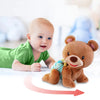 A baby is interacting with an interactive musical crawling bear toy.