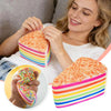 A woman is assembling a rainbow layer cake squishy toy with colorful frosting and stripes.