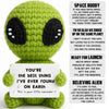 Handmade crochet alien plush toy in lime green with black eyes and a sign