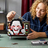 A woman is assembling a horror movie puppet model kit with a voice recorder on a green table.