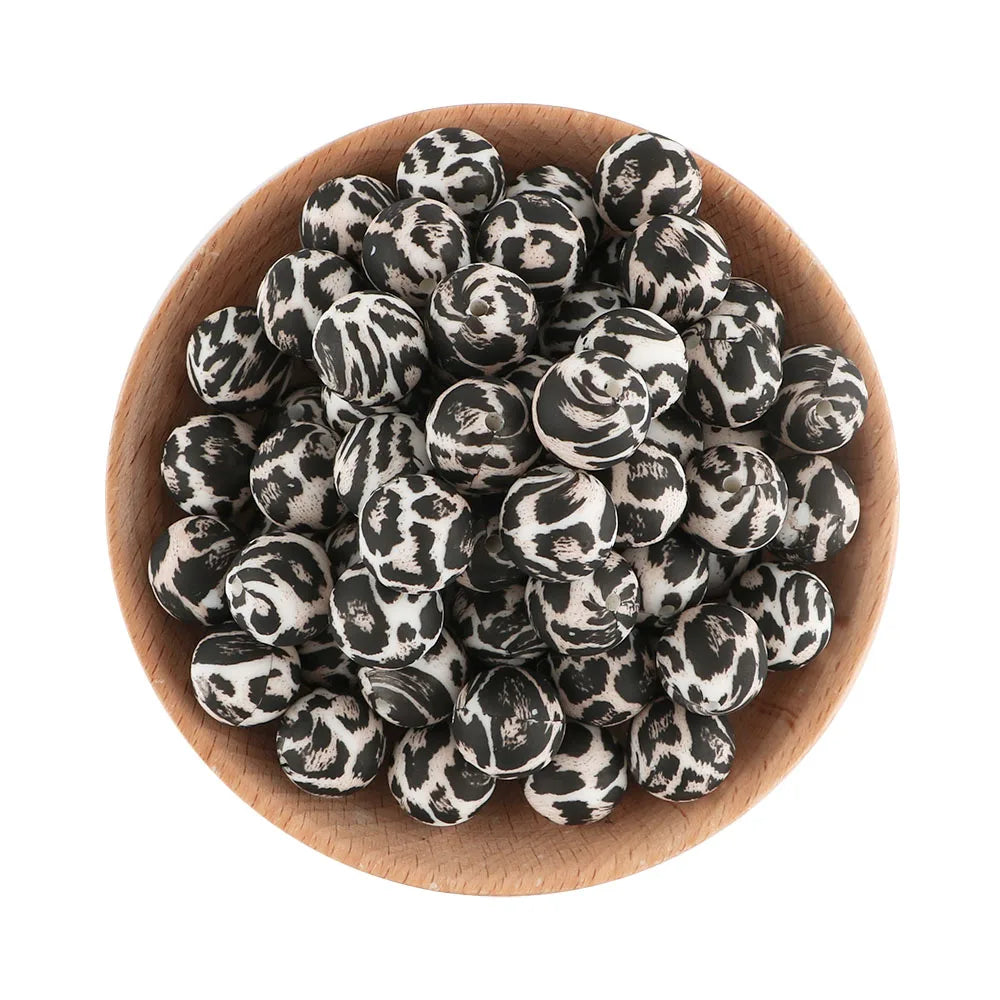 A pile of small, round black and white patterned silicone beads in a wooden bowl.