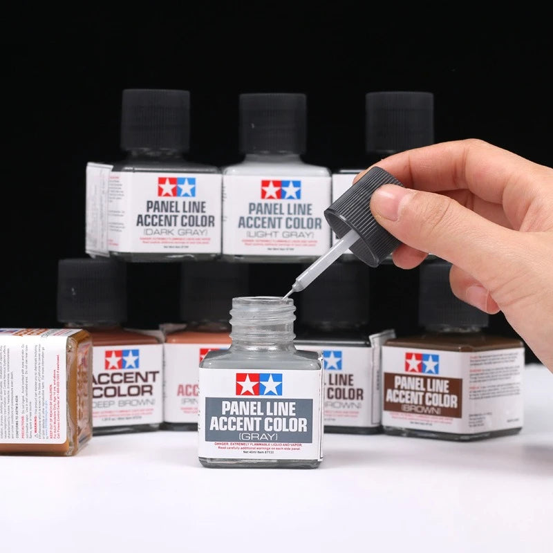 A hand is applying Panel Line Accent Color paint to a bottle of Panel Line Accent Color paint.