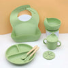 A light green silicone baby tableware set including a feeding plate, bowl, cup, and spoon.