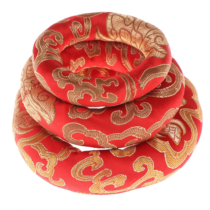 A handmade red singing bowl cushion featuring intricate gold embroidery.