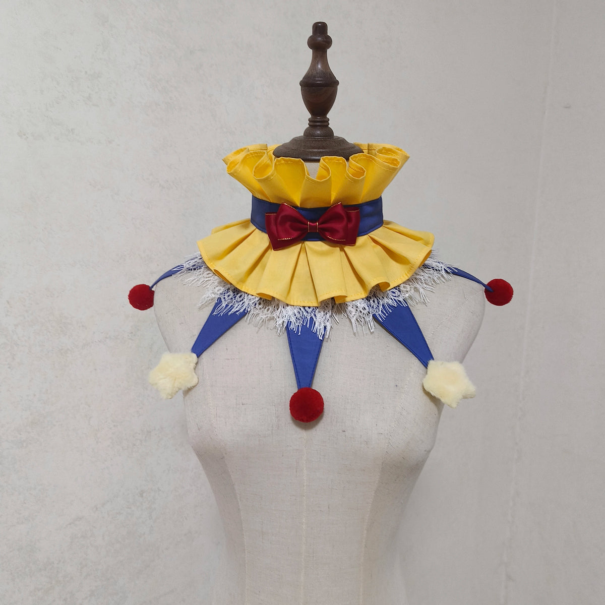 Handmade colorful clown ruff collar with yellow fabric, red bow, and blue trim displayed on a mannequin.