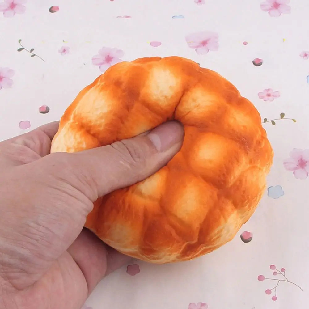 A hand is squeezing an orange, dough-like bread toy for stress relief and sensory play.